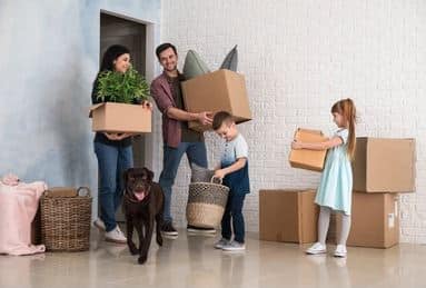 Family moving cardboard boxes into new house